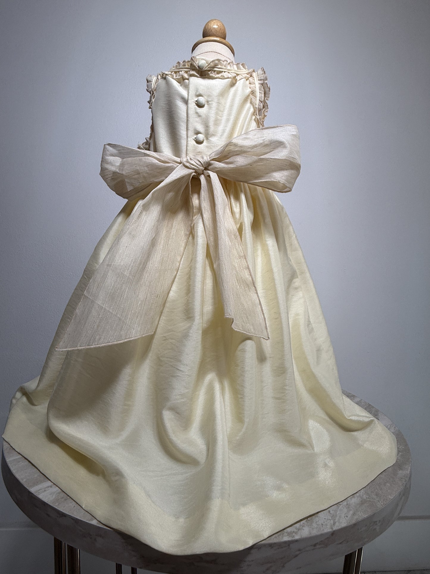 White dress with a large bow on a mannequin against a gray background