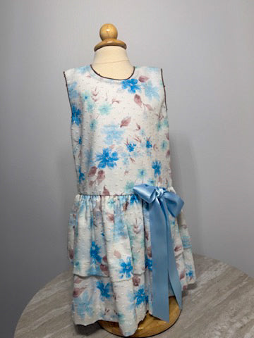 Floral dress with a blue ribbon on a mannequin against a gray background
