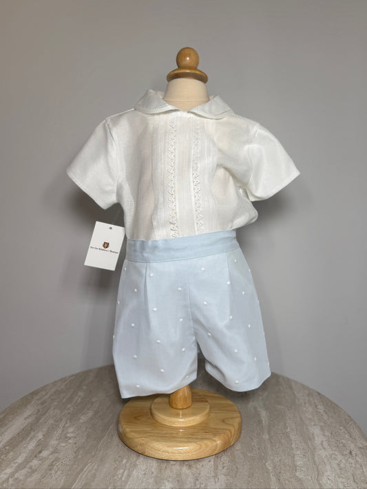 White shirt and light blue shorts set on a mannequin with a gray background